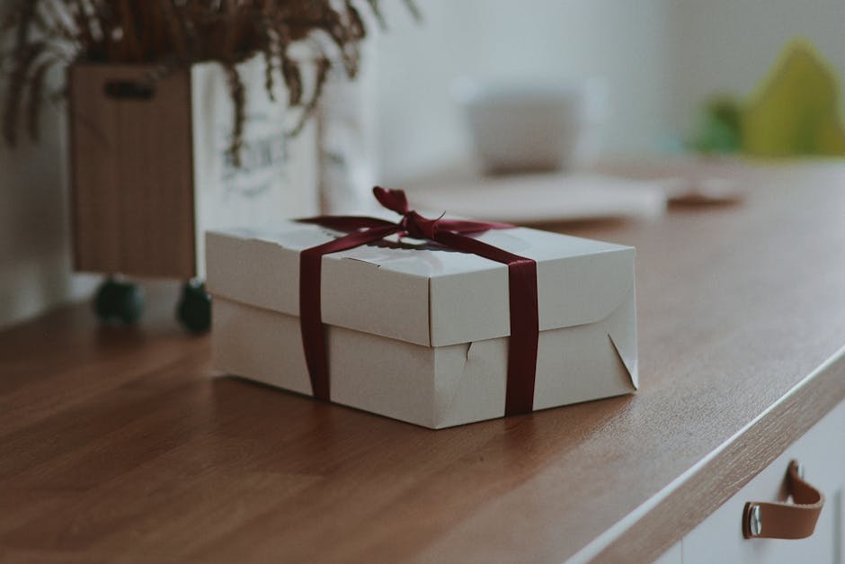 A white gift box with a red ribbon on a wooden surface, adding a touch of elegance and anticipation.