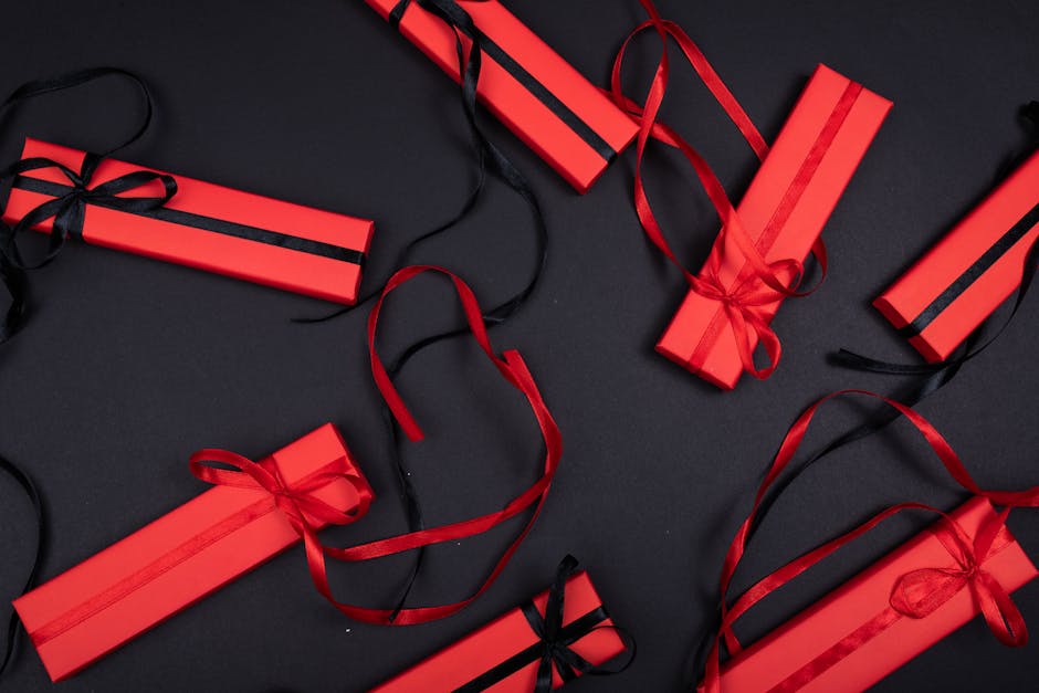 Red gift boxes with black ribbons arranged on a black background, captured from above.
