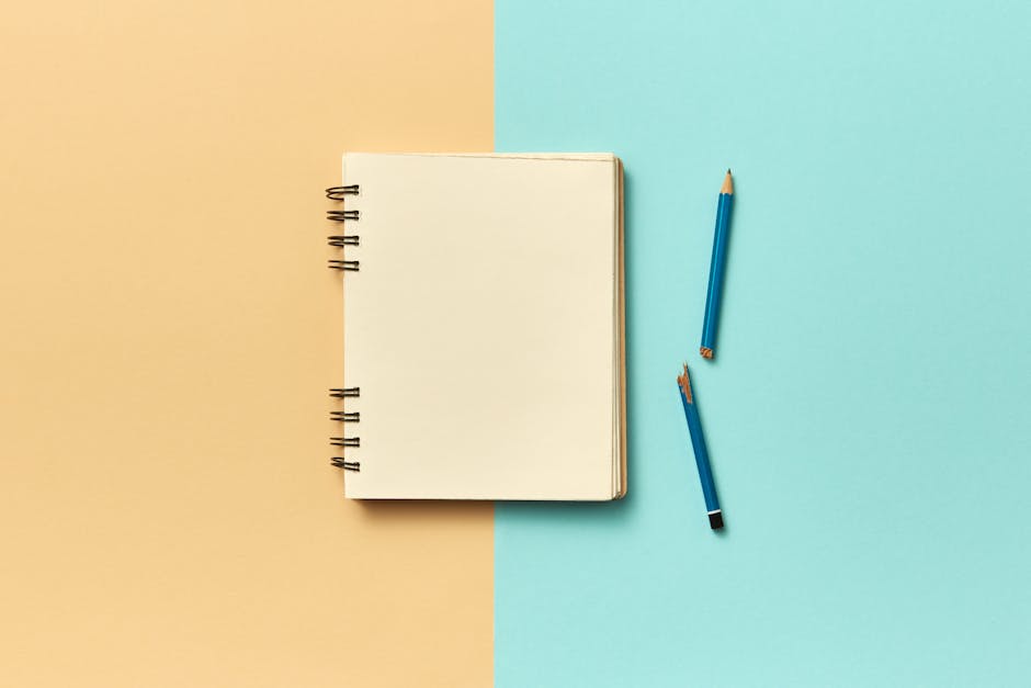 A simple notebook and two pencils on a split pastel background create a minimalist design.