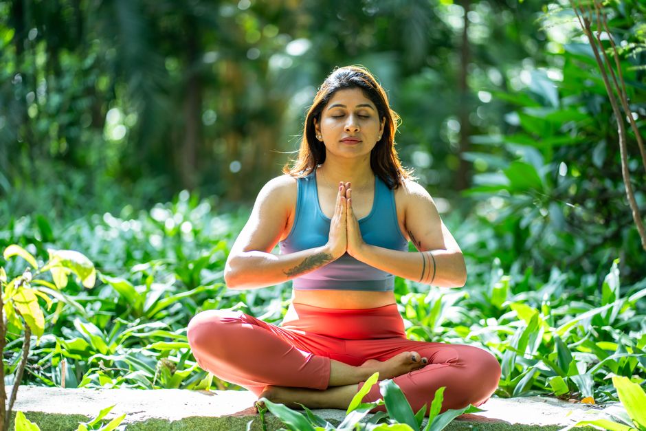 Serene woman practicing yoga in a lush green garden, focusing on mindfulness and relaxation.