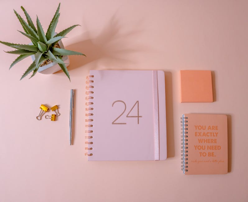 Stylish flat lay of a minimalist workspace with peach tones, featuring a planner, notebooks, and stationery.